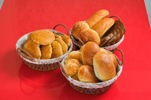 three baskets filled with different types of bread on a red table at Gunesh Hotel Samarkand in Khodzha-Akhrar