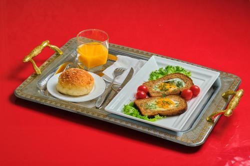 a tray with a plate of food and a glass of orange juice at Gunesh Hotel Samarkand in Khodzha-Akhrar
