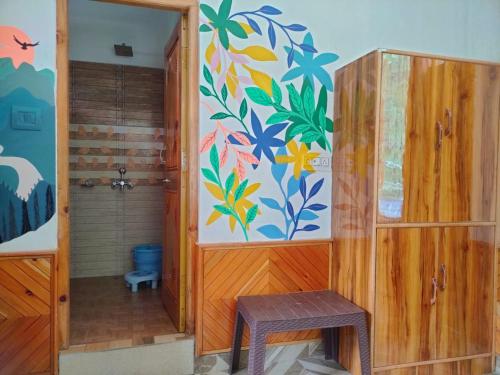a bathroom with a toilet and a painting on the wall at Highland Gojh Kasol in Kasol