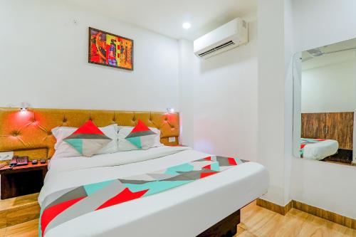 ein Schlafzimmer mit einem großen weißen Bett mit einer farbenfrohen Tagesdecke in der Unterkunft FabExpress The Mall Inn in Kānpur