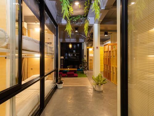 Habitación con un pasillo con camas y plantas. en Khao San Social Capsule Hostel en Bangkok