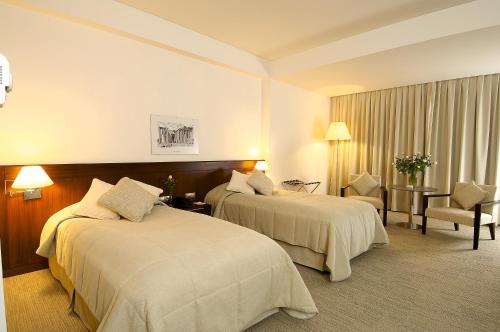a hotel room with two beds and a chair at Ontur Izmir Otel in Izmir