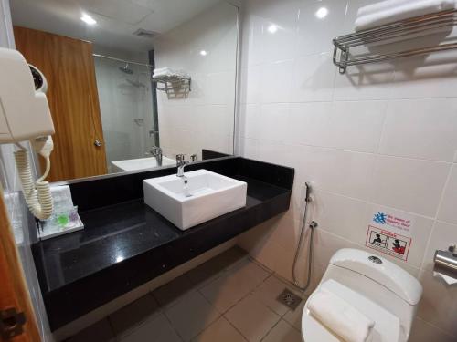 een badkamer met een wastafel, een toilet en een spiegel bij TD CAPITAL HOTEL in Inanam