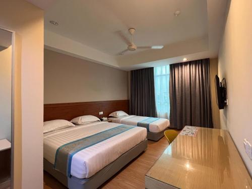 a hotel room with two beds and a window at TD CAPITAL HOTEL in Inanam