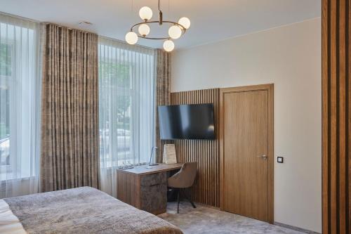 a bedroom with a desk and a tv and a bed at Vvinn Hotel in Vilnius