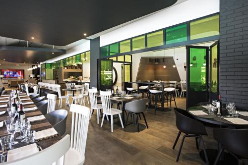 a restaurant with tables and white chairs and a bar at Novotel Milano Linate Aeroporto in Milan