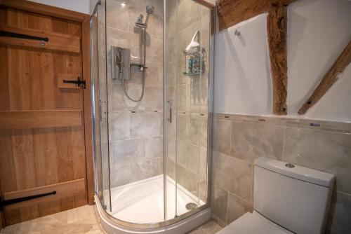 a bathroom with a shower and a toilet at Bramble Cottage - Cosy 2 Bed With Deluxe HOT TUB & Log Burner in Hereford