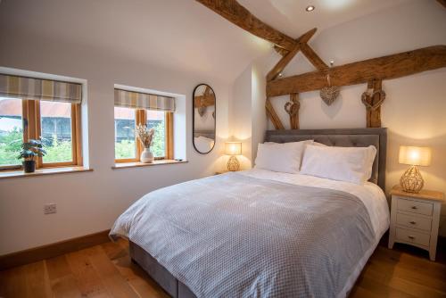 a bedroom with a bed and two windows at Bramble Cottage - Cosy 2 Bed With Deluxe HOT TUB & Log Burner in Hereford