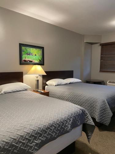 a bedroom with two beds and a tv on the wall at Plaza Inn in Sabetha