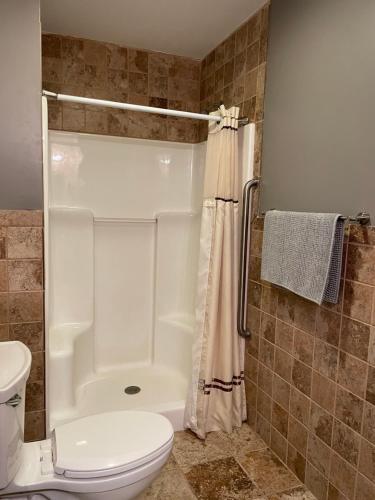 ein Badezimmer mit einem weißen WC und einer Dusche in der Unterkunft Plaza Inn in Sabetha