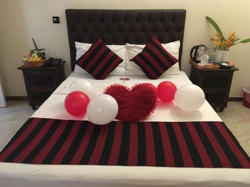 a bed with red and white balloons and two hearts at Forever City Hotel in Kiribathgoda