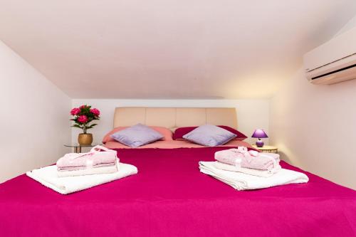 a bedroom with a large pink bed with towels on it at Malinsummer Apartments in Malinska