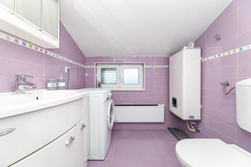 une salle de bains pourpre avec un lavabo et des toilettes. dans l'établissement Malinsummer Apartments, à Malinska