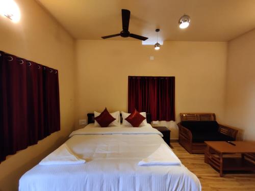 una camera da letto con un letto e un ventilatore a soffitto di Forest and River Edge Resort a Kannur