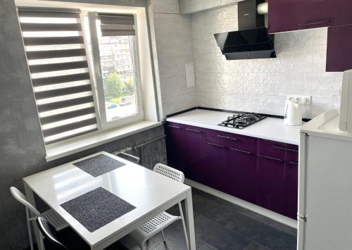 a kitchen with purple cabinets and a white table at Двокімнатна на Оболоні біля Дрім-Тауна in Kyiv