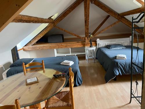 a bedroom with two beds and a table in a attic at Demeure du NID de la Création in Vertou
