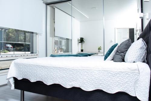 um quarto com uma cama grande com lençóis brancos e almofadas em Talo saunalla ja sähköauton oma Type2 latauspiste em Vantaa