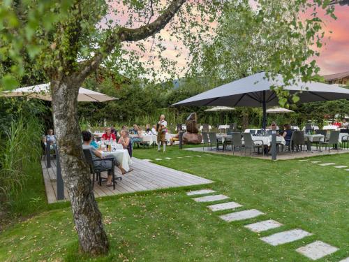 a group of people sitting at tables under umbrellas at Sporthotel Austria in Sankt Johann in Tirol