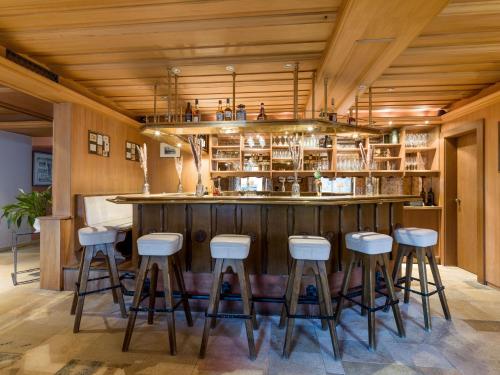 a bar with stools in a room with wooden ceilings at Sporthotel Austria in Sankt Johann in Tirol