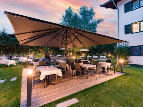 a wooden deck with tables and chairs and an umbrella at Sporthotel Austria in Sankt Johann in Tirol