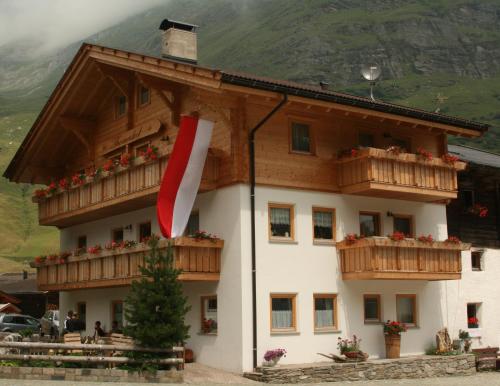 a building with wooden balconies and a flag on it at Thomashof in Pfelders