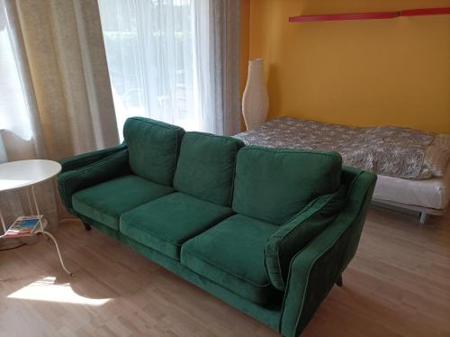 ポズナンにあるDarna Apartamenty Avena 1のリビングルーム(緑のソファ、ベッド付)