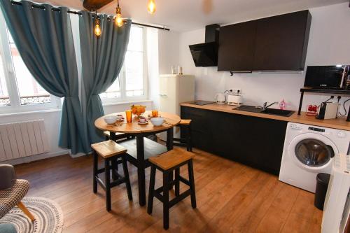 une petite cuisine avec une table et une cuisine avec un lave-linge dans l'établissement Au Fil du Temps, à Sélestat