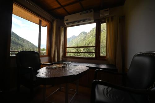 a table and chairs in a room with a window at The Hillside in Kasol