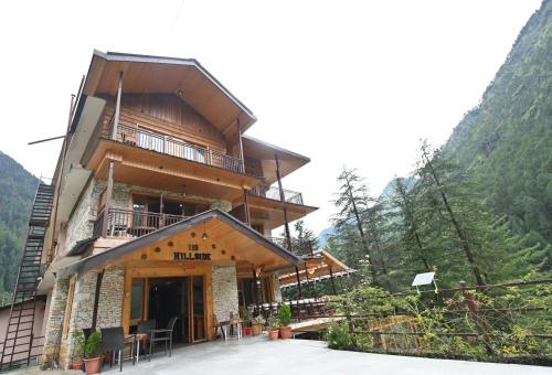 a large wooden building with a balcony in the mountains at The Hillside in Kasol
