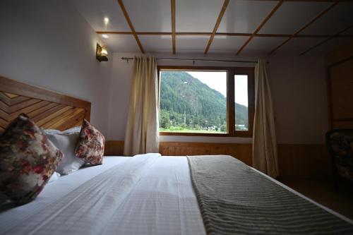 a bedroom with a bed with a large window at The Hillside in Kasol