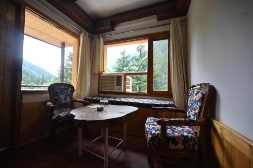 a room with two chairs and a table and a window at The Hillside in Kasol