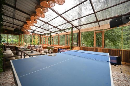 a ping pong table in a room with a glass ceiling at The Hillside in Kasol