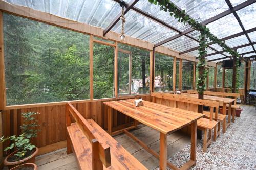 a conservatory with a wooden table and benches at The Hillside in Kasol