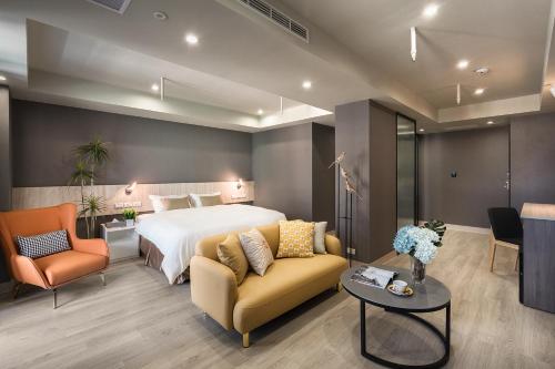 a hotel room with a bed and a couch and chair at Comma Boutique Hotel in Taipei