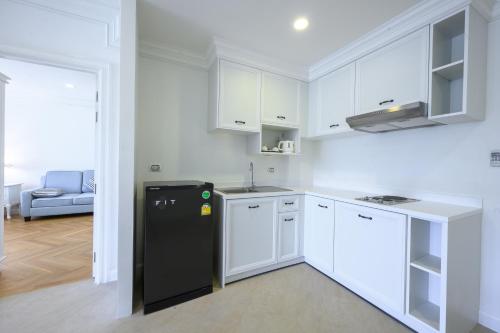 a kitchen with white cabinets and a black refrigerator at Chateau de Khaoyai Hotel & Resort in Khao Yai