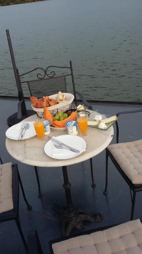een tafel met een dienblad met eten en drinken op een boot bij Péniche Chopine in Beaucaire