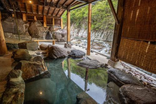 una gran piscina de agua en una habitación con rocas en Nikko Nationalpark Kawamata Onsen KURA, en Nikko