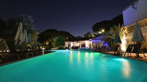 a large swimming pool at night with umbrellas at Le Confidentiel Hôtel & SPA in Saint-Raphaël