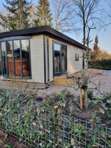 una piccola casa con tetto nero in un giardino di Cozy chalet for 4 Veluwe a Putten