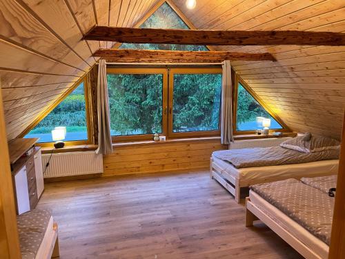 a room with two beds and windows in a log cabin at Wioska Kowala in Tyrawa Wołoska