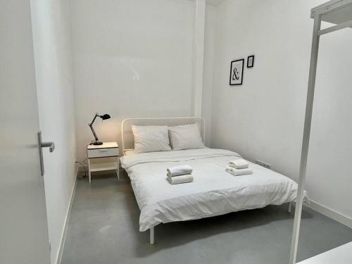 een witte slaapkamer met een bed met handdoeken erop bij Trendy 2 Bedroom Serviced Apartment in Rotterdam