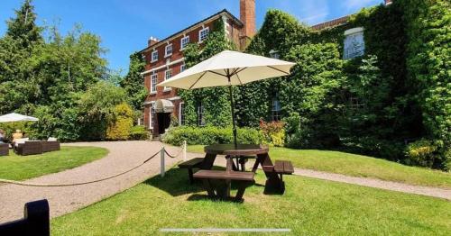 a picnic table with an umbrella in the grass at Park House Hotel in Shifnal