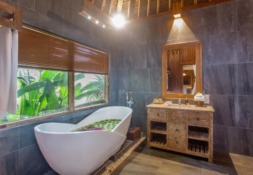 ein Bad mit einer Badewanne, einem Waschbecken und einem Fenster in der Unterkunft Manah Shanti Suites by Pramana Villas in Ubud