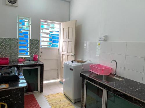 a small kitchen with a sink and a refrigerator at Homestay Teratak Kasih Astana height in Sandakan