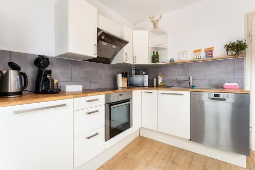 a kitchen with white cabinets and stainless steel appliances at Stay Awesome - Familien-Apartment am Botanischen Garten Kassel in Kassel