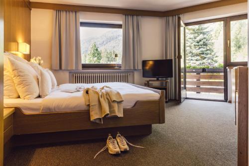 a hotel room with a bed with two pairs of shoes at Hotel Auren in San Giovanni in Val Aurina