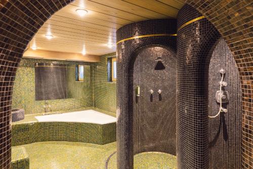 a bathroom with a shower and a tub and a sink at Hotel Auren in San Giovanni in Val Aurina