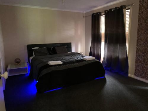 um quarto com uma cama preta e luzes azuis em Golf View Charm em Craigieburn