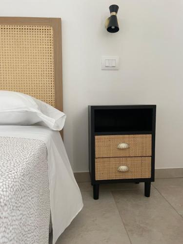 a bedroom with a bed and a night stand with a drawer at Dimorae Camà in Cisternino