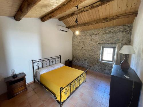 ein Schlafzimmer mit einem gelben Bett und einer Ziegelwand in der Unterkunft Agriturismo Tenuta Feraudo in Labonia